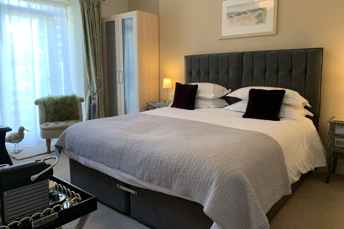 Quarto de hotel com uma cama grande, uma cadeira, um abajur e um quadro na parede.