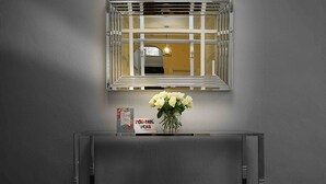 A console table with a mirror above it, a vase with white flowers, and a thank you card. - Twelve Holiday Apartments (Blackpool)