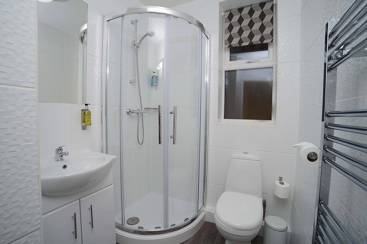 A modern bathroom with a glass-enclosed shower, a white sink, and a toilet.