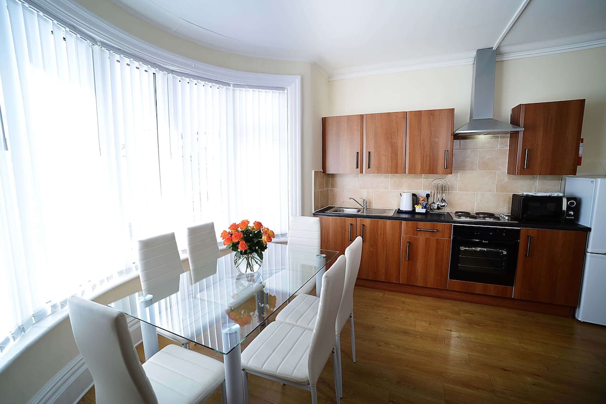 A modern kitchen with wooden cabinets, a glass dining table, and white chairs.