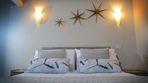 A neatly made bed with patterned pillows and a headboard, two wall-mounted star-shaped light fixtures, and a plain wall. - Twelve Holiday Apartments (Blackpool)