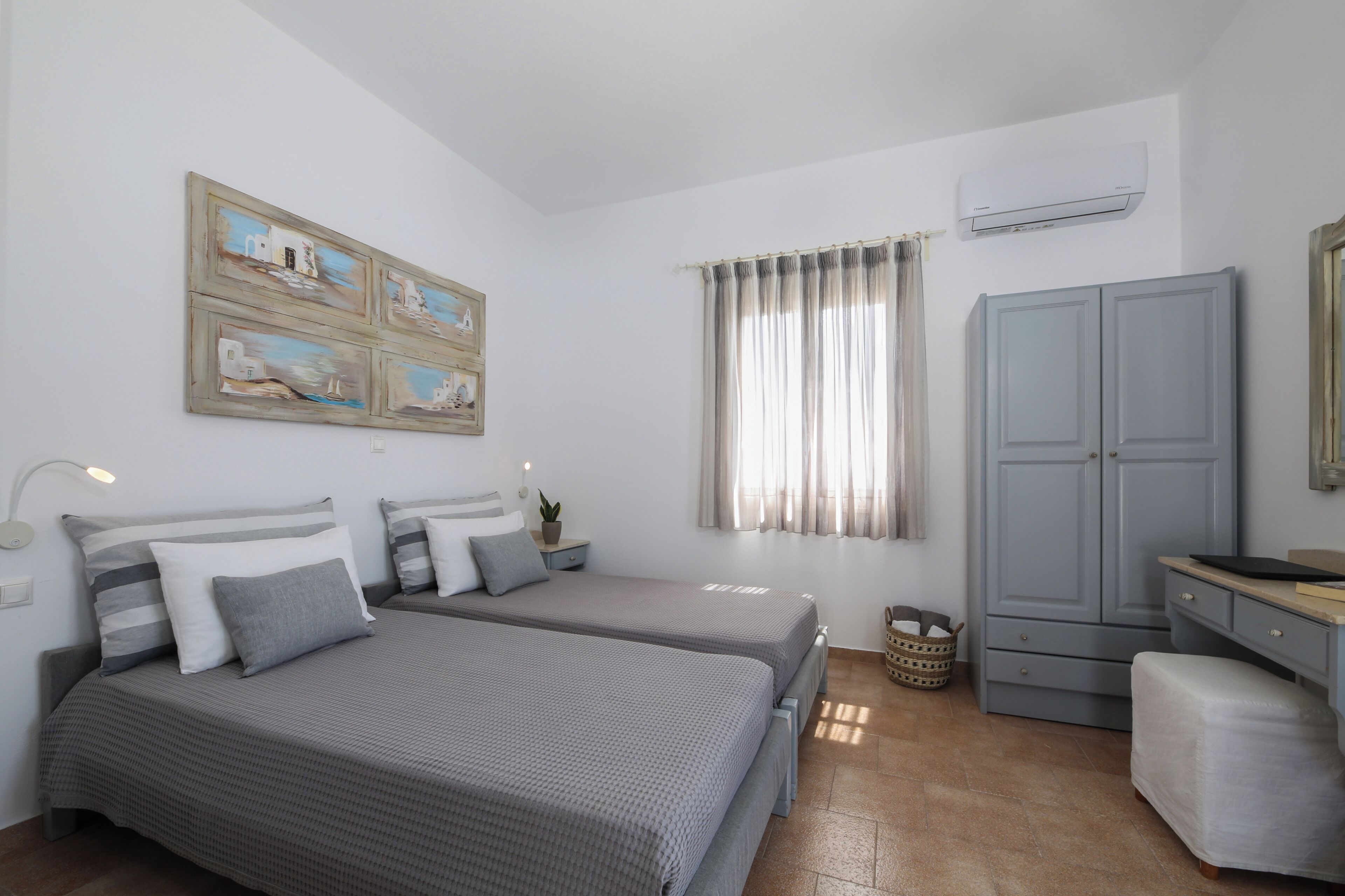 A bedroom with two beds, a wardrobe, a desk, and a window with curtains.