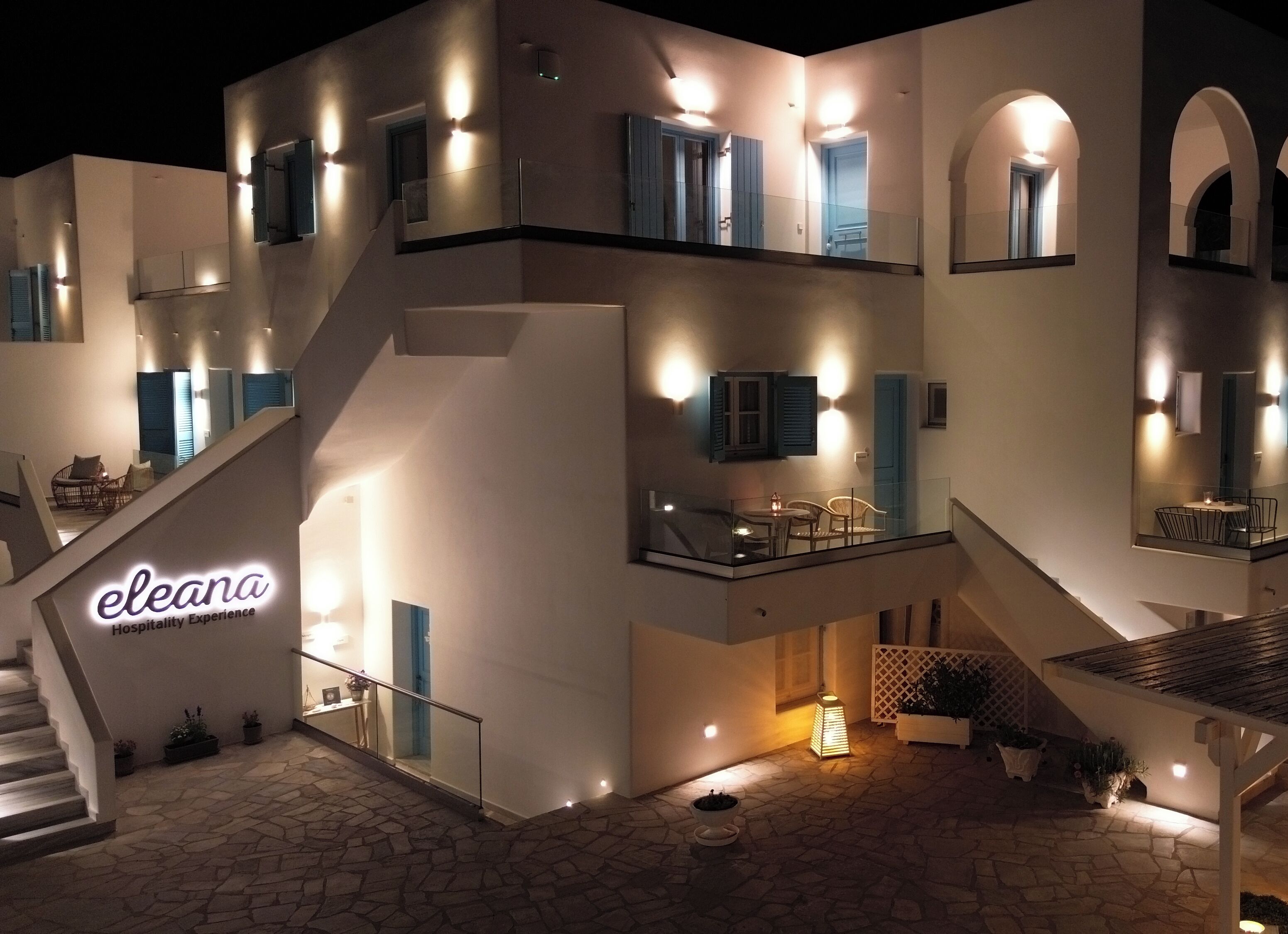 A multi-story building with a staircase, outdoor seating area, and a sign reading 'eleana Hospitality Experience'.
