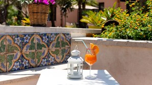 A table with a glass of orange juice, a lantern, and a wicker basket with flowers. - Hotel Achibea (San Vito Lo Capo)