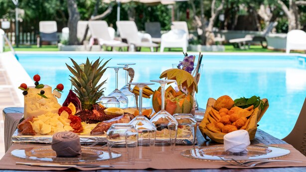 A poolside buffet with various fruits, cheeses, and snacks. - Hotel Achibea (San Vito Lo Capo)