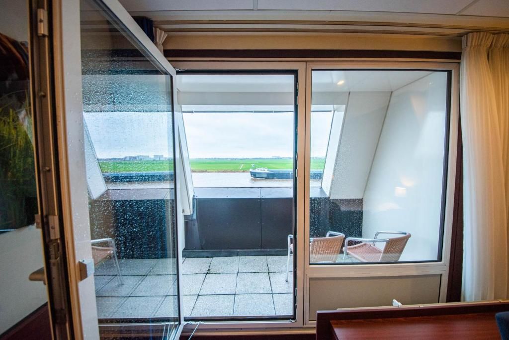 A room with a sliding glass door leading to an outdoor area with a view of a green field and a building in the distance.