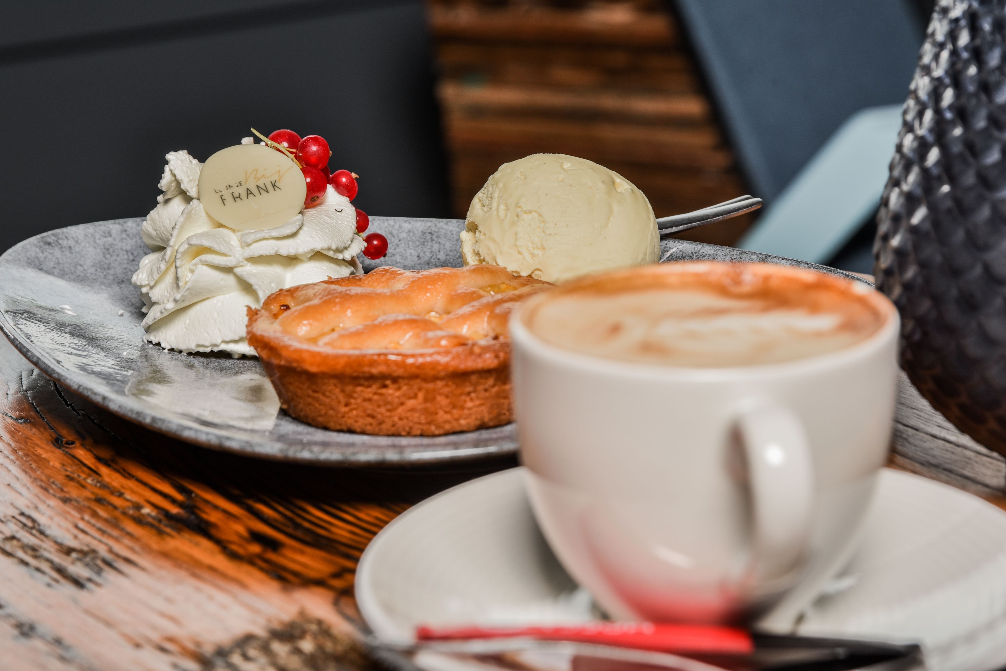 A dessert plate with ice cream and a muffin, a cup of coffee, and a spoon on a table.