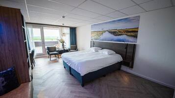 Una habitació d'hotel amb un llit, una taula de treball i vista a l'exterior.