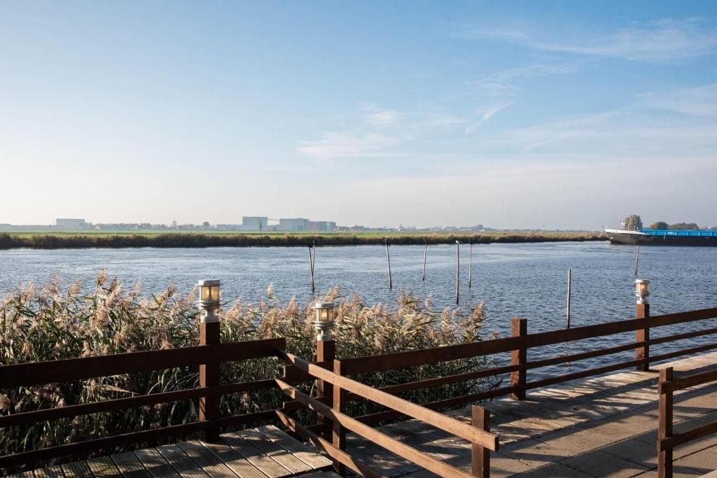 A wooden deck overlooking a calm river with distant buildings.