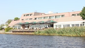 A waterfront building with outdoor seating and a dock. - Hotel Zwartewater (Zwartsluis)