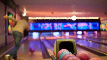 Een bowlingbaan met een persoon op de voorgrond en meerdere banen op de achtergrond.