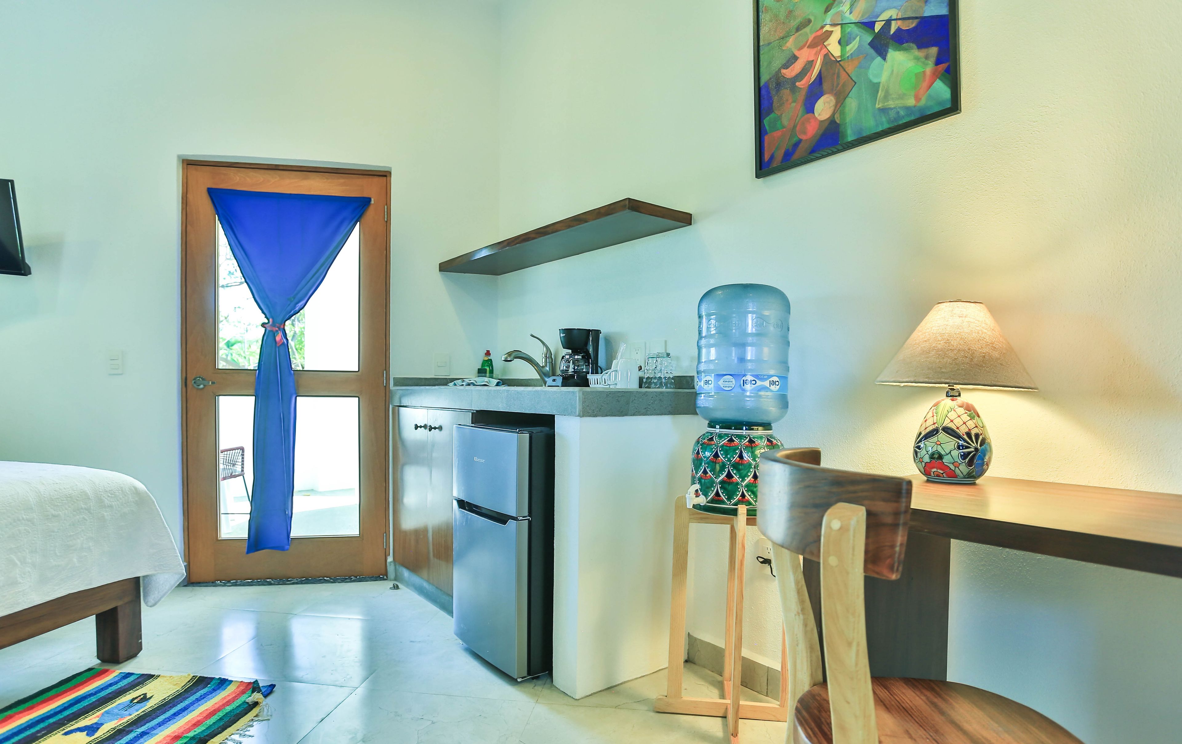 A compact kitchen with a refrigerator, a water dispenser, and a coffee maker.