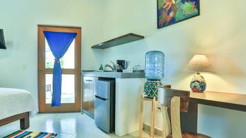A compact kitchen with a refrigerator, a water dispenser, and a coffee maker.
