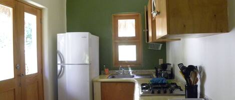 A compact kitchen with a refrigerator, sink, and stove.