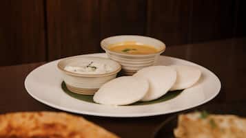 A plate with three bowls of food and three flatbreads on a table.