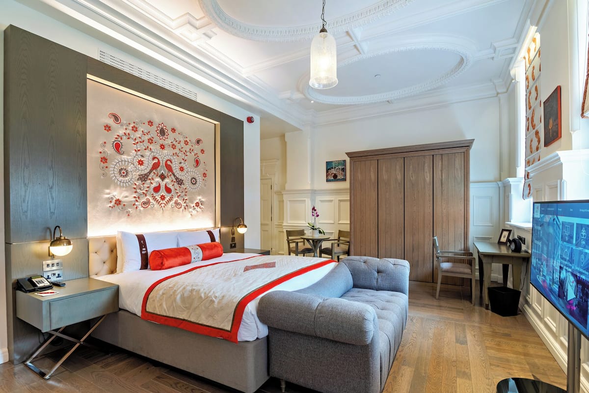 Relax in this stylish room with a large bed, sofa, and desk, perfect for unwinding and staying connected.