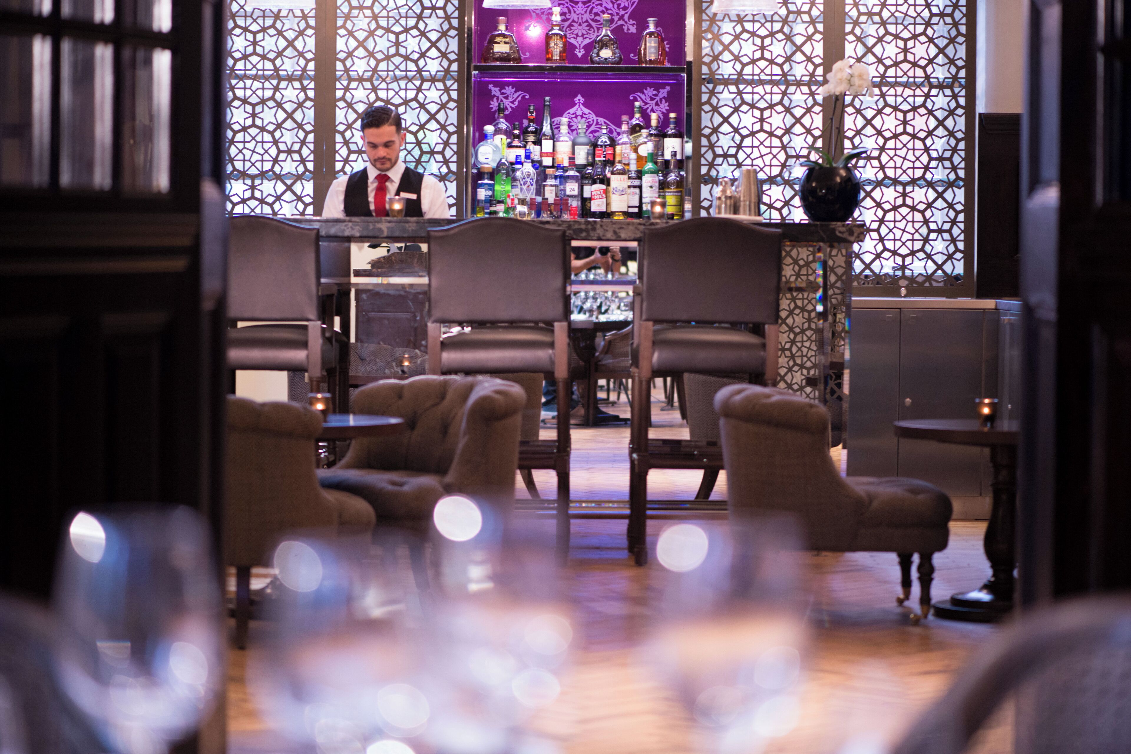 A bar area with a bartender, bar counter, and seating arrangement.
