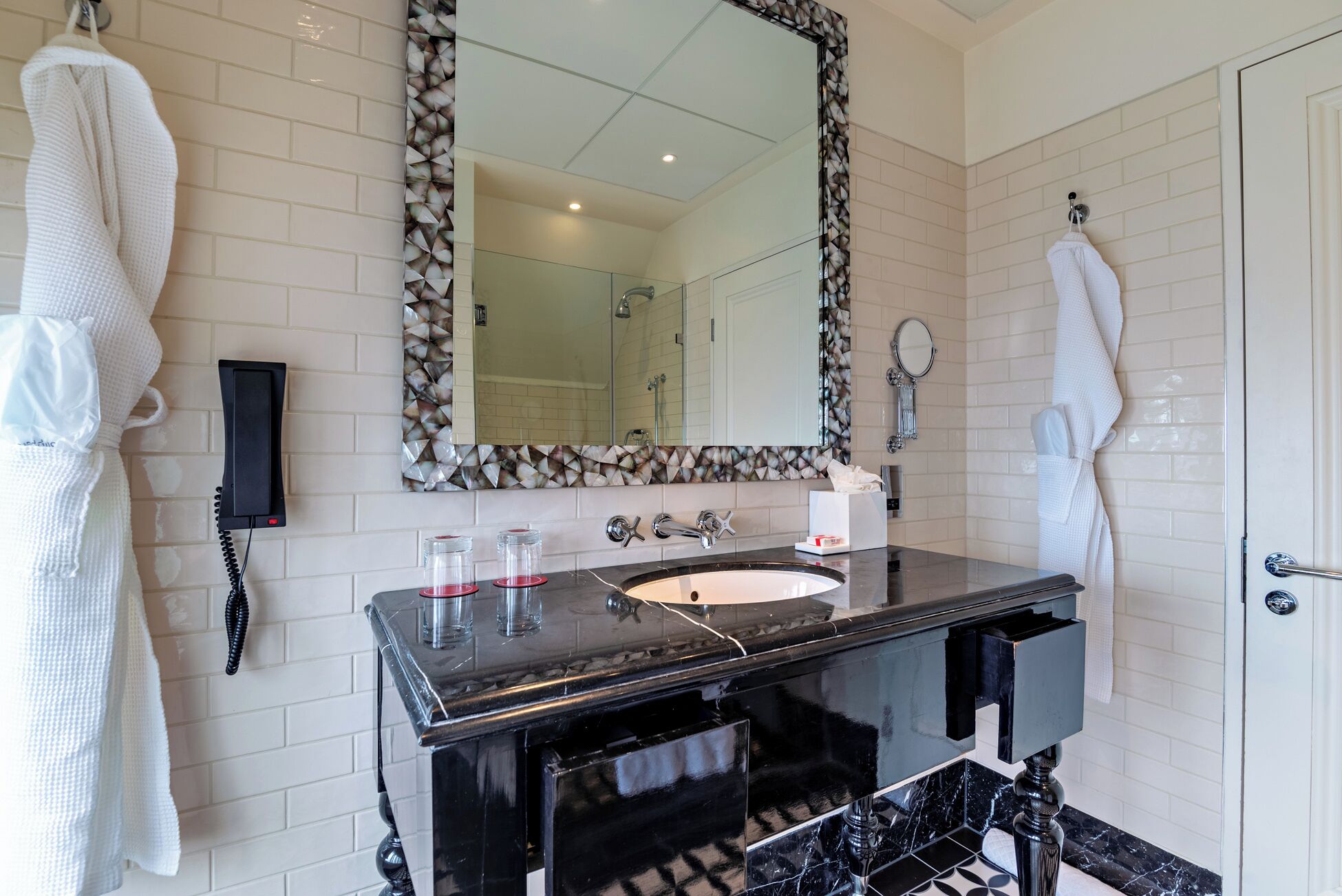 A bathroom with a black vanity, a large mirror, and two white towels hanging on the wall.