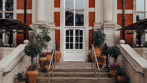 A grand entrance with a white door, flanked by columns and a decorative arch. - The Lalit London (London)