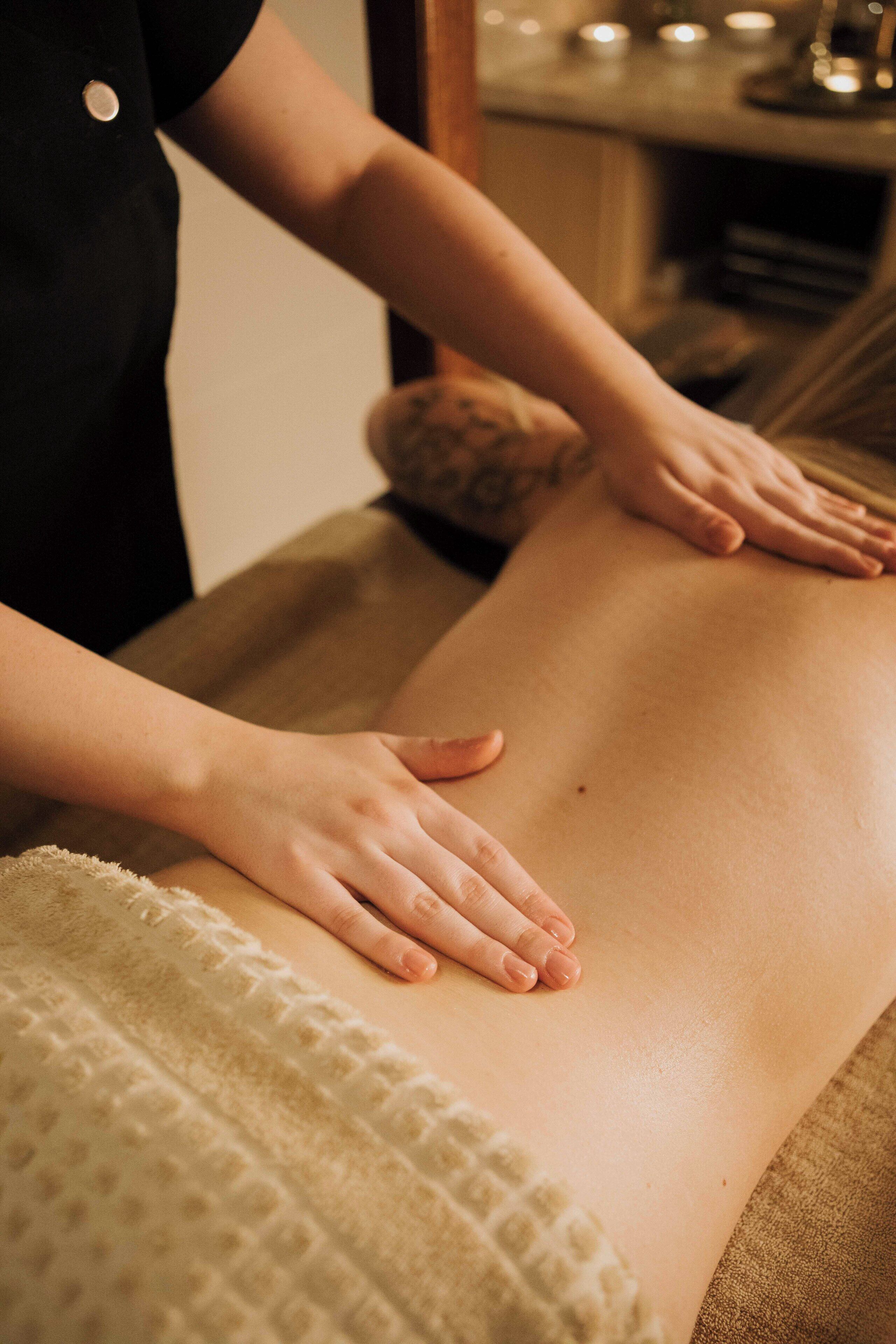 Eine Massageanwendung: Eine Person erhält eine Rückenmassage auf einer Massageliege.