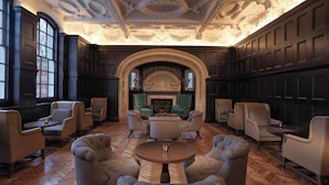 A grand room with a fireplace, multiple armchairs, and a large wooden floor.