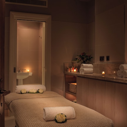 A spa room with a massage table, a sink, and candles.