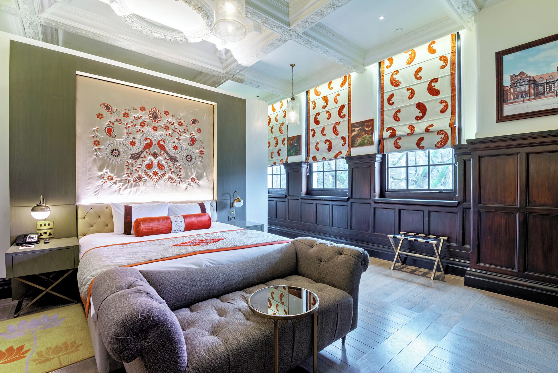 A hotel room with a large bed, a seating area, and a view of the city through large windows.