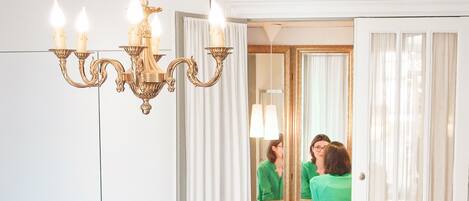 A bathroom with a chandelier, a mirror, and a toilet.
