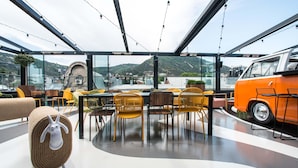A modern dining area with a glass ceiling, yellow chairs, and a vintage orange van. - Ibis Styles Tbilisi Center (Tbilisi)