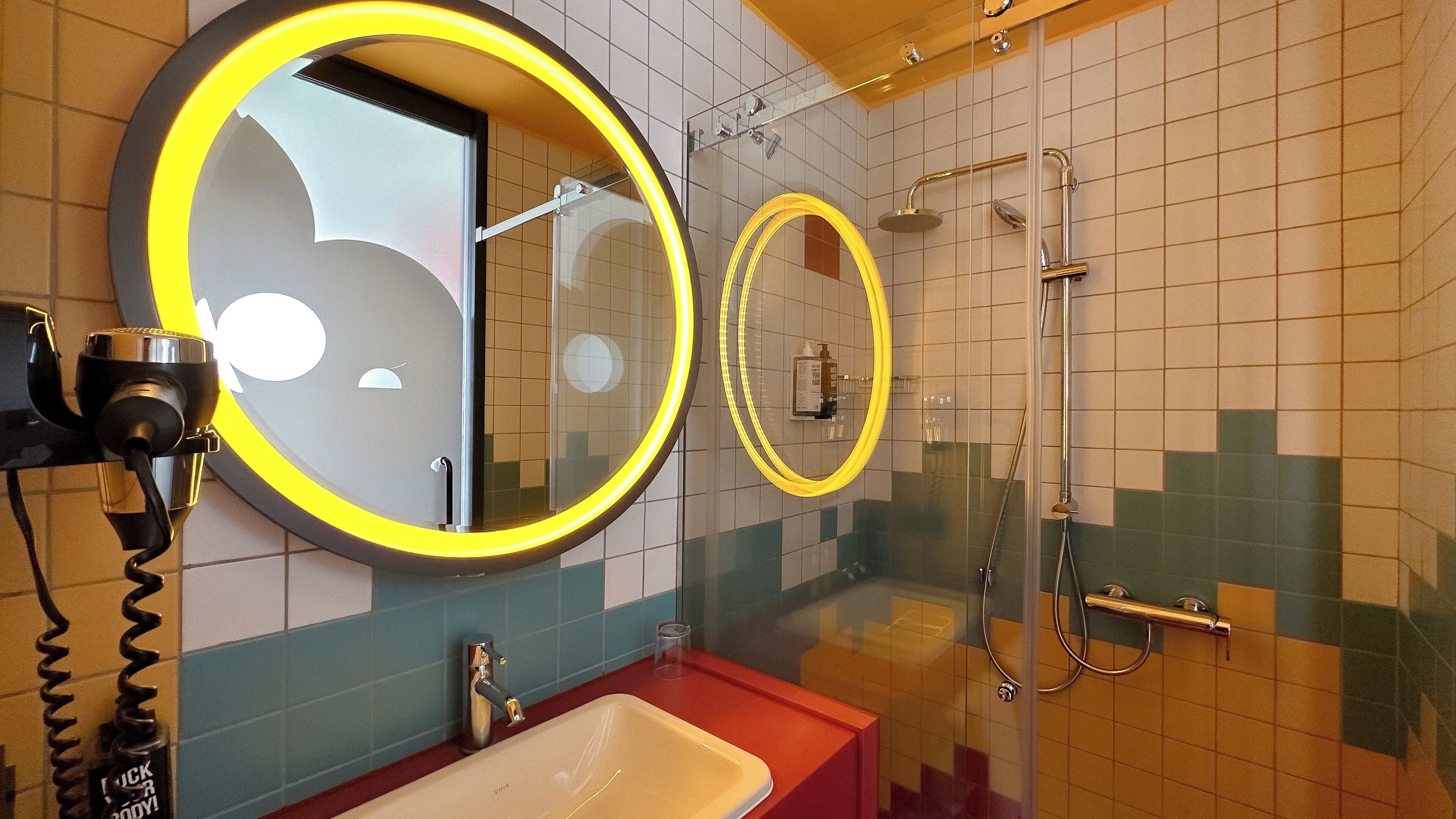 Un baño con dos espejos redondos, un lavabo y una ducha.