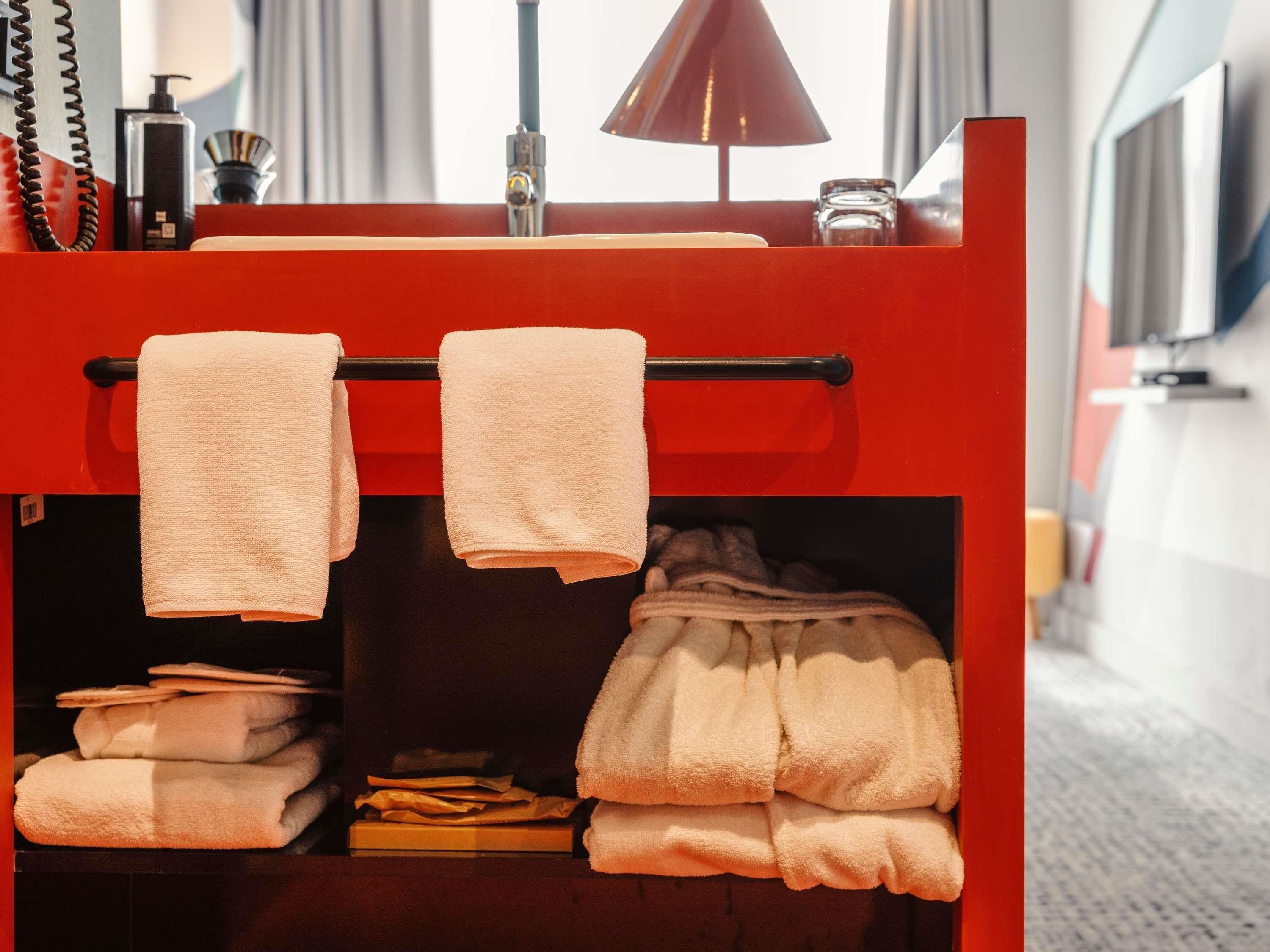Een rode minibars met handdoeken en toiletartikelen.