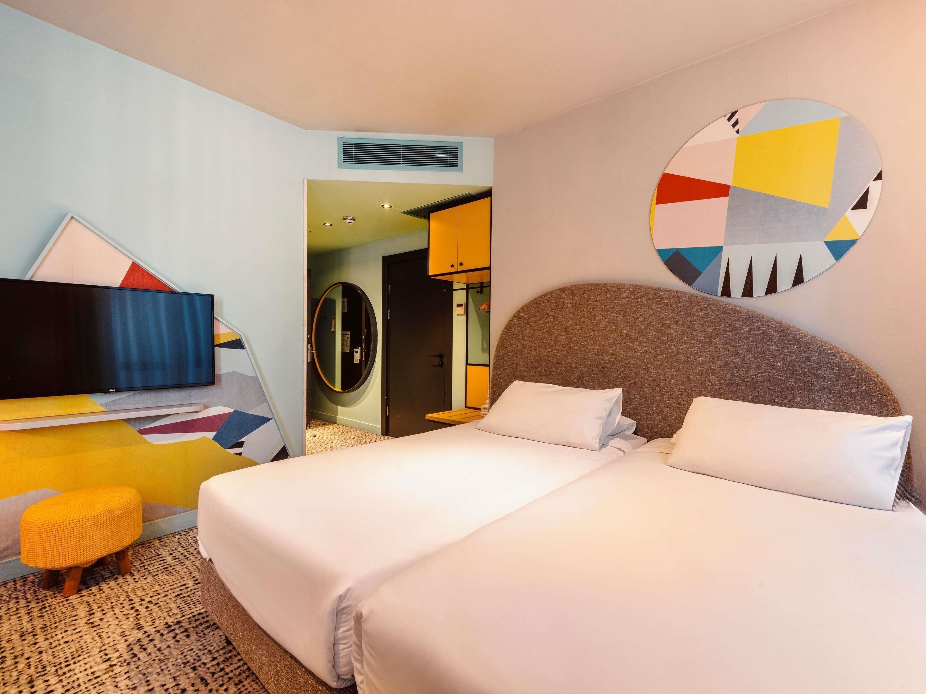 A hotel room with a bed, a television, and a circular wall decoration.