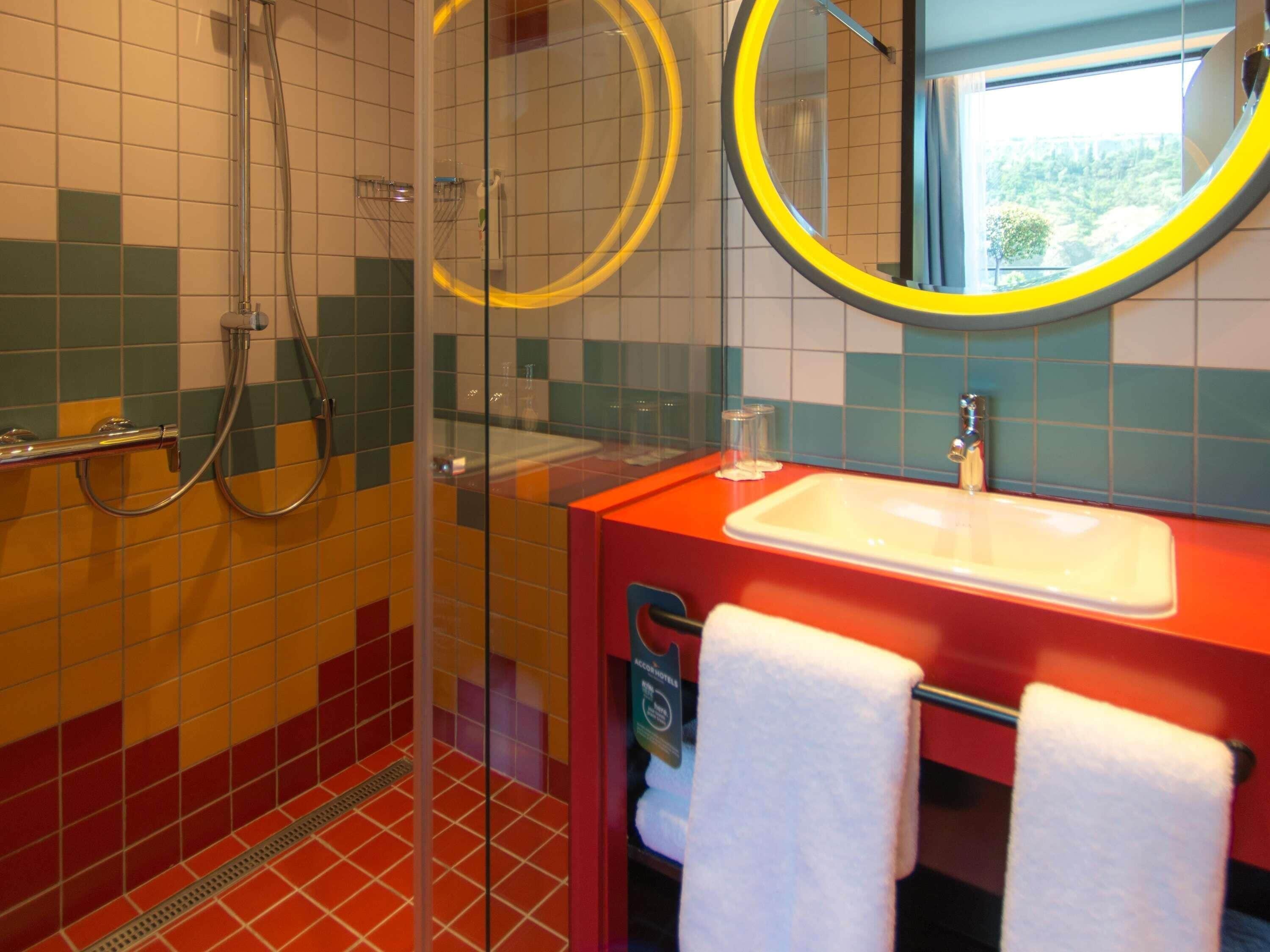 A bathroom with a glass shower enclosure, a sink with a mirror, and a towel rack.