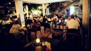 Un comedor interior con mesas y sillas, una escalera y vistas al exterior.