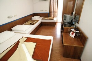 A hotel room with two beds, a television, a small table with a bottle and glasses, and a mirror. - Beach Hotel (Podgora)