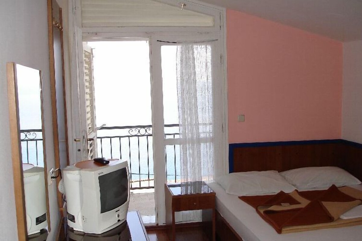 Ein Hotelzimmer mit einem Bett, einem Fernseher, einem Sessel und einem Balkon mit Blick.