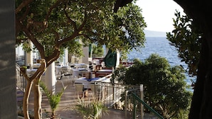 Una terraza con asientos al aire libre, vista al mar y plantas en macetas.