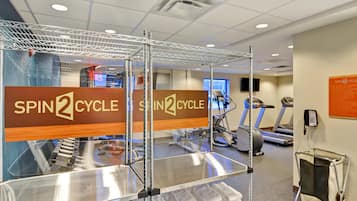 A gym with spin cycle equipment, treadmills, and a phone for assistance.
