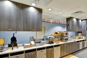 A modern kitchen area with a long counter, equipped with various appliances and a coffee machine.