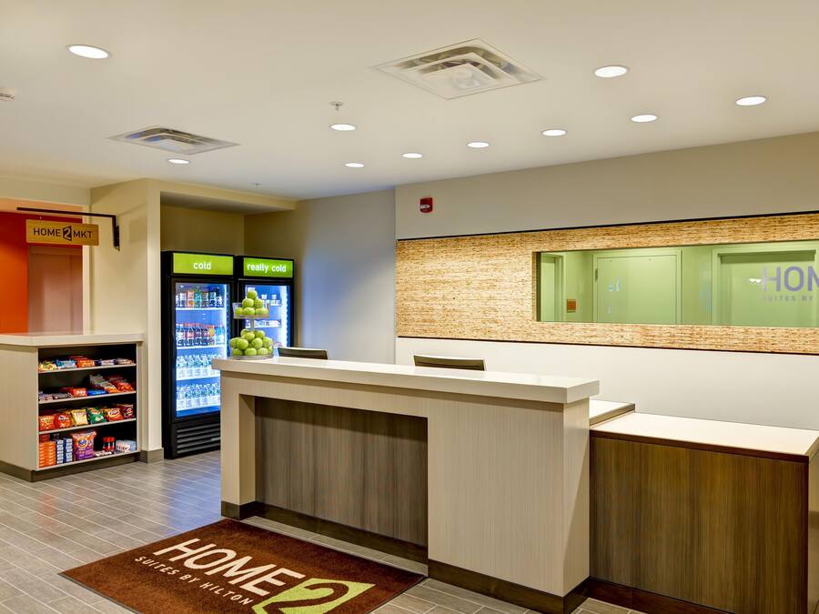 A hotel reception area with a reception desk, a vending machine, and a wall-mounted information display.