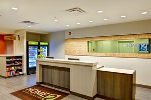 A hotel reception area with a reception desk, a vending machine, and a wall-mounted information display. - Home2 Suites by Hilton Dickson City Scranton (Scranton)