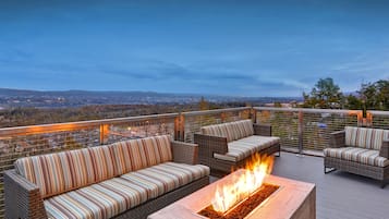 Terraza en la azotea con mobiliario de mimbre y una chimenea.