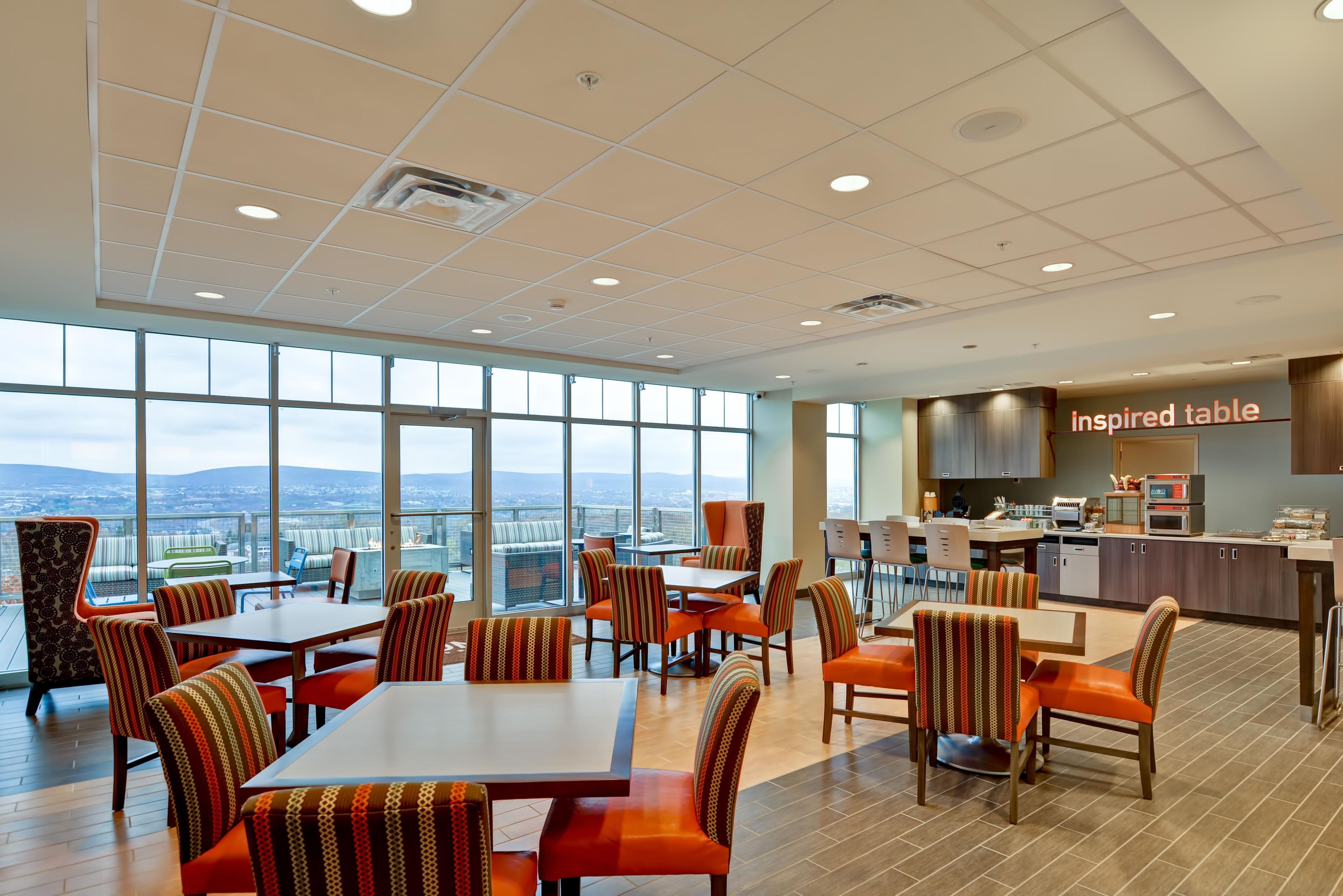 A spacious dining area with high ceilings, large windows, and a view of the cityscape.