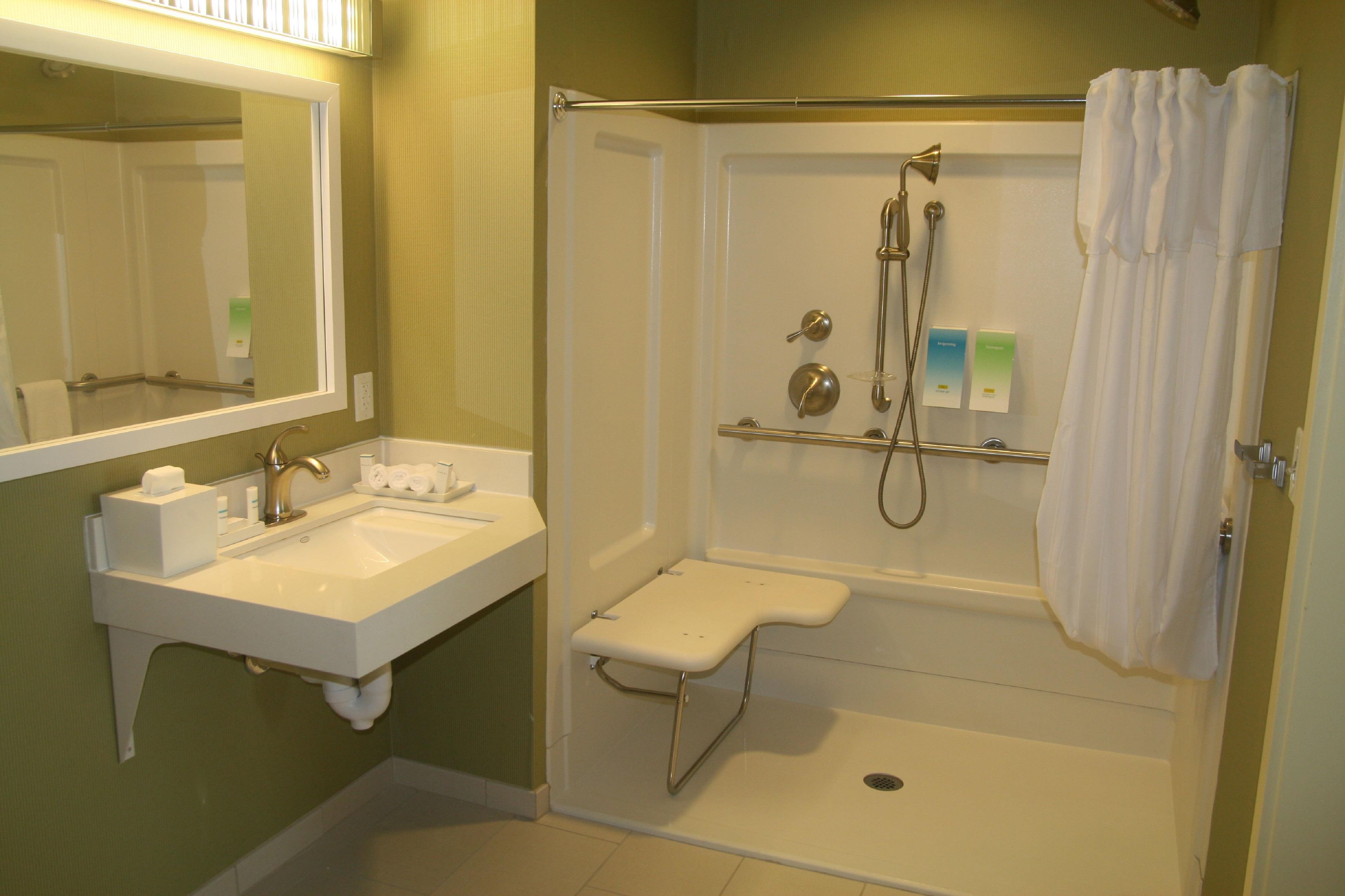 A bathroom with a sink, mirror, shower, and toilet.