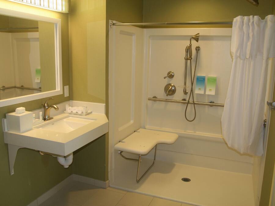 A bathroom with a sink, mirror, shower, and toilet.