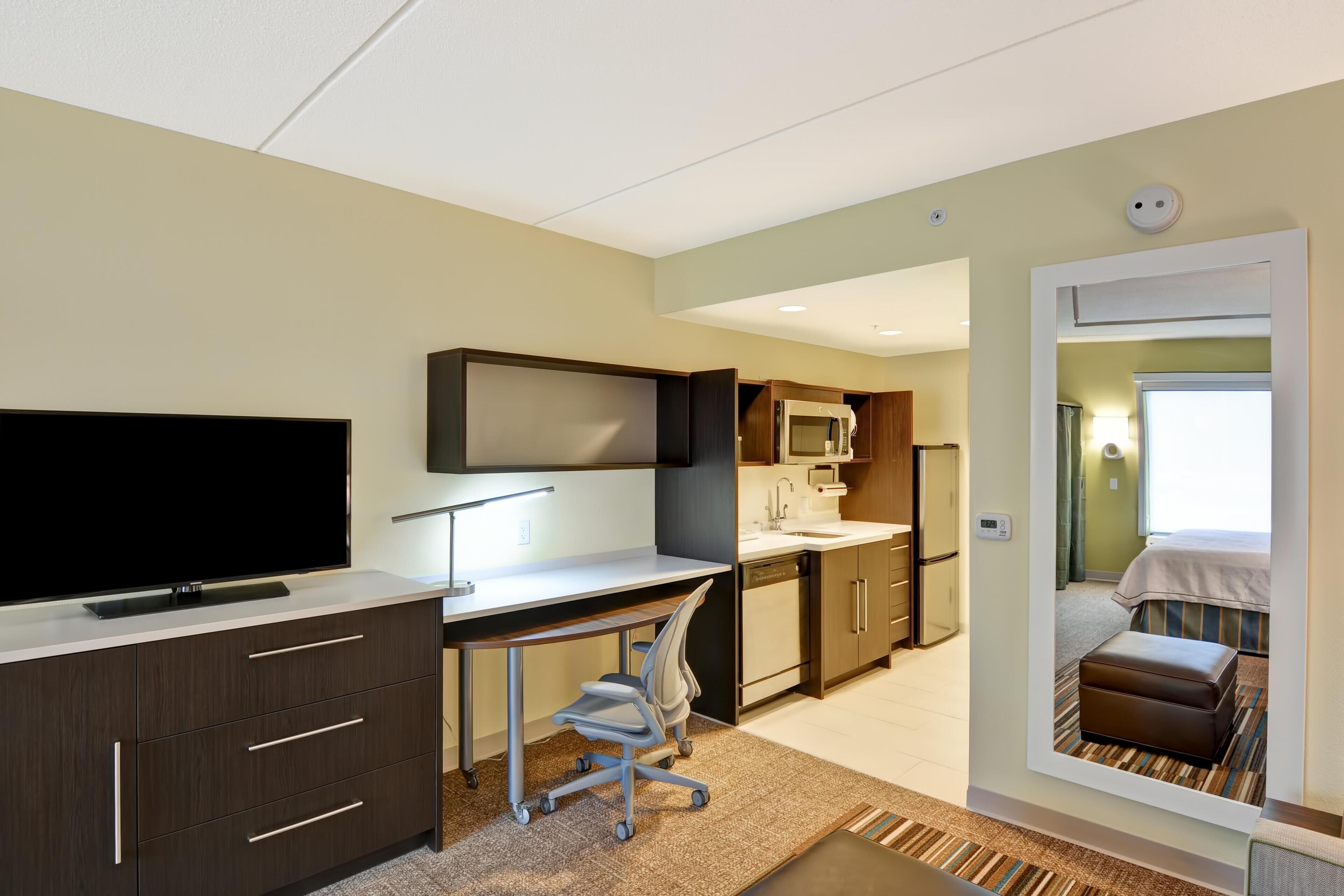 Une chambre d’hôtel équipée d’un bureau, d’une télévision, d’une kitchenette et d’un lit.