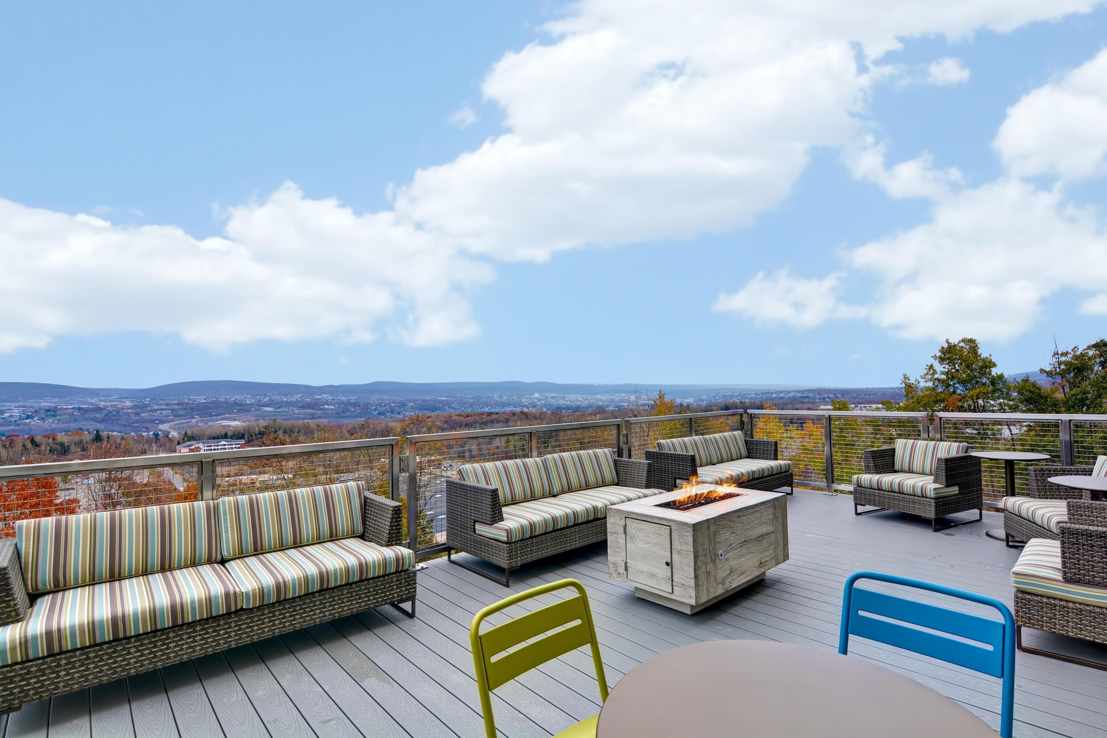 Una terraza con mobiliario de mimbre, un hogar y vistas del paisaje.
