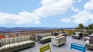 Una terraza con mobiliario de mimbre, un hogar y vistas del paisaje.