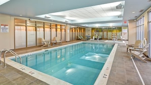 Una piscina interior con agua cristalina, paredes de azulejos e iluminación empotrada en el techo.