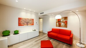 Un salon moderne avec un canapé rouge, un meuble blanc et deux pommes vertes posées sur le meuble.